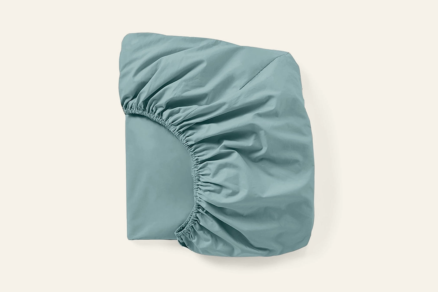 Corner detail of Coyuchi Refined Percale fitted sheet in muted teal, showing elastic gather.