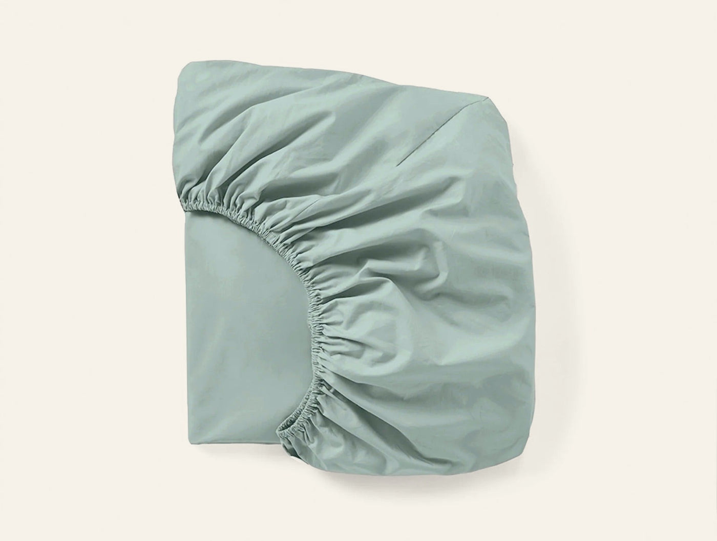 Sage green fitted sheet folded to show elasticized corner and smooth percale weave.