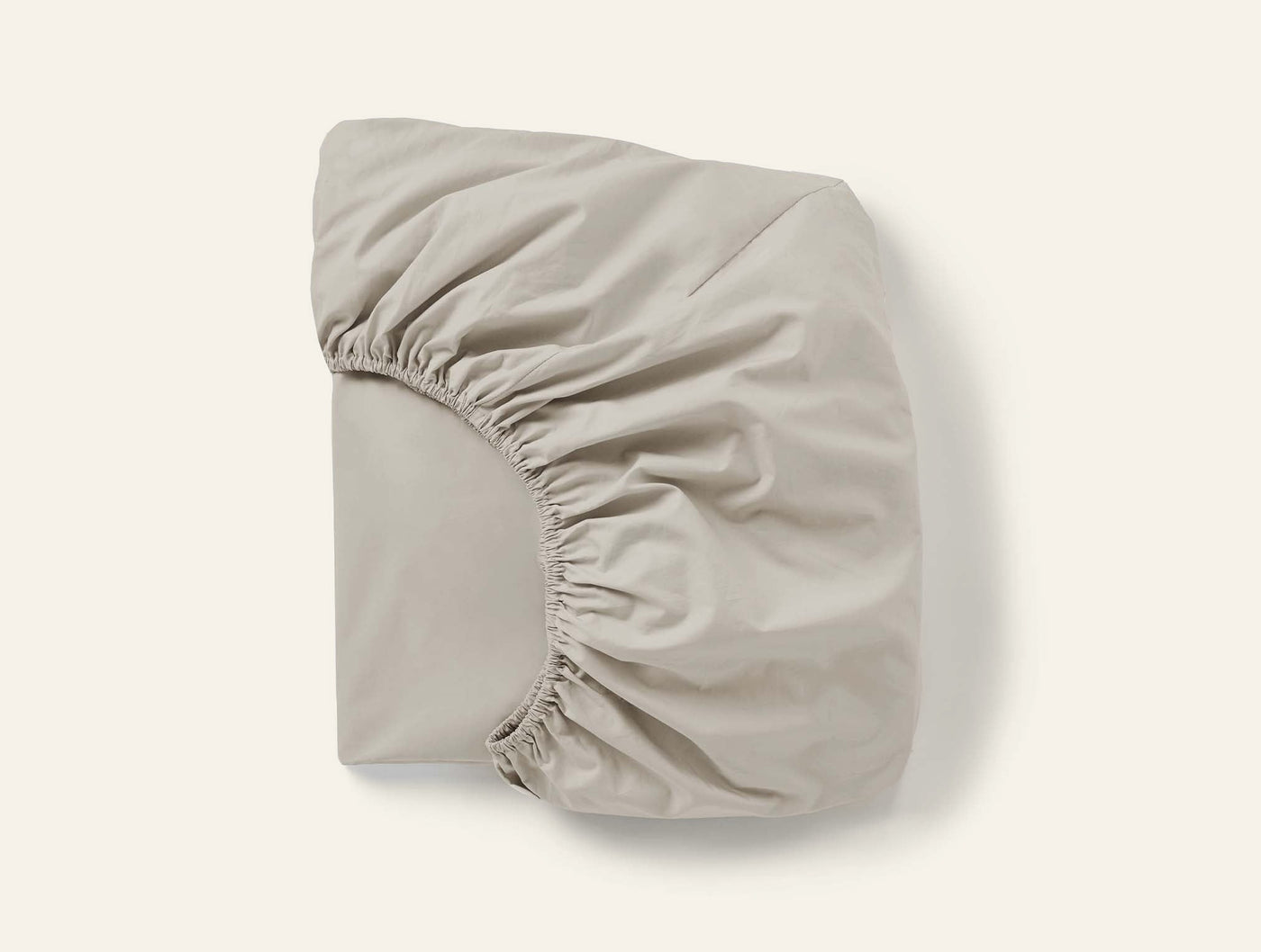 Coyuchi Refined Percale fitted sheet folded to show elasticated corners, stone.
