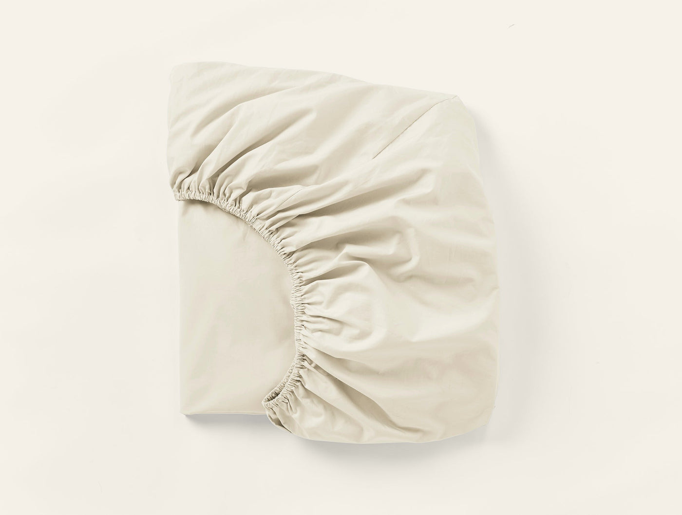 Ivory fitted sheet folded to show elasticated corners and smooth percale weave.