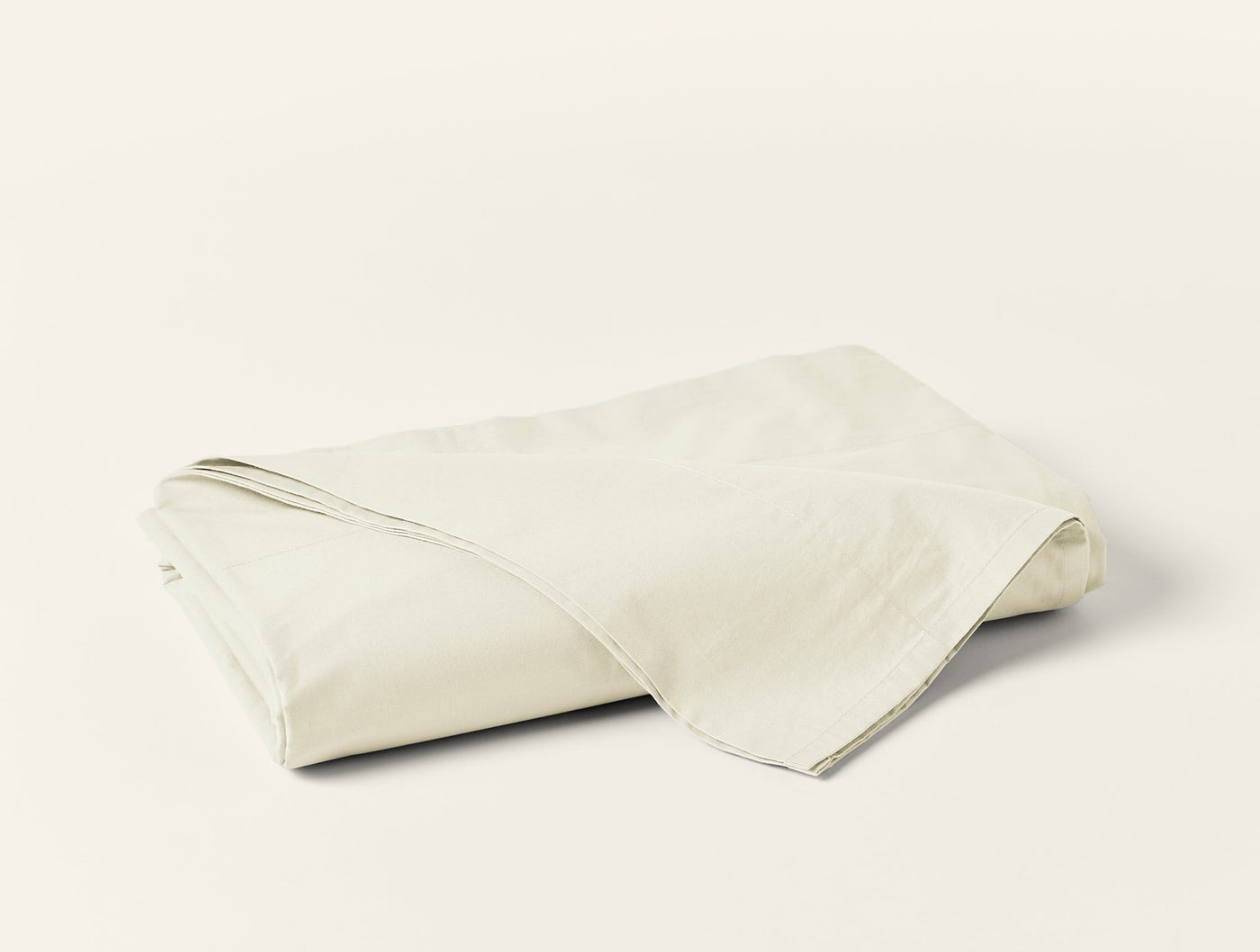 Folded ivory Coyuchi Refined Percale flat sheet showing smooth, crisp cotton fabric.
