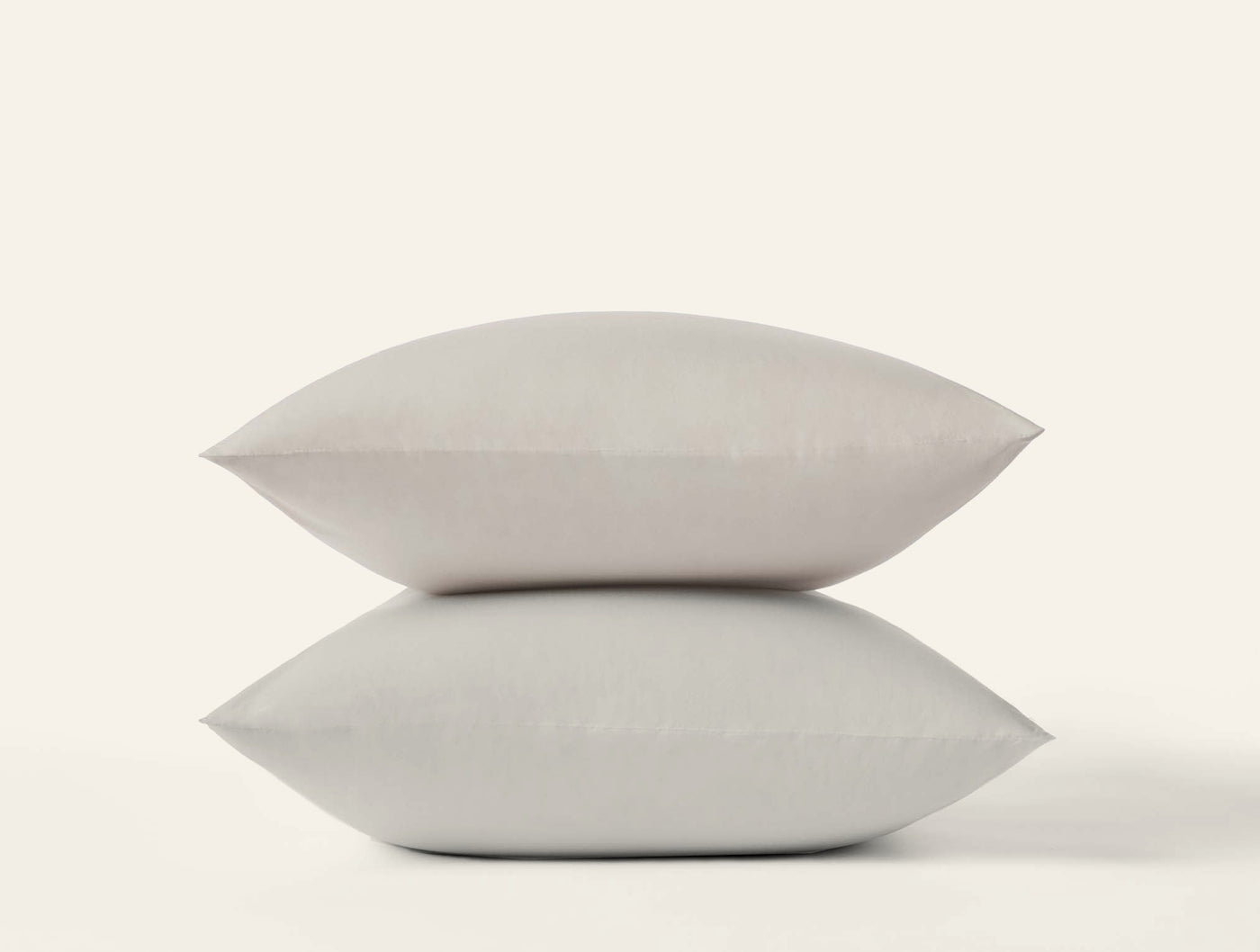 Two stacked Coyuchi Refined Percale pillowcases in stone, smooth matte finish against white background.