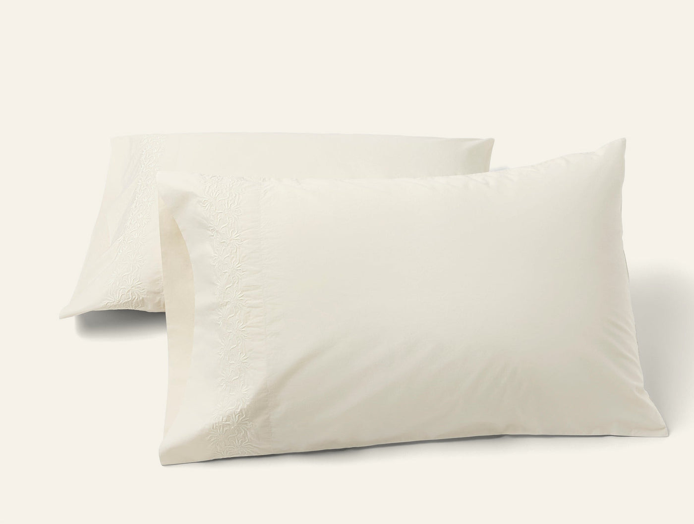 Pair of Coyuchi Refined Percale pillowcases in ivory, shown stacked on white background.