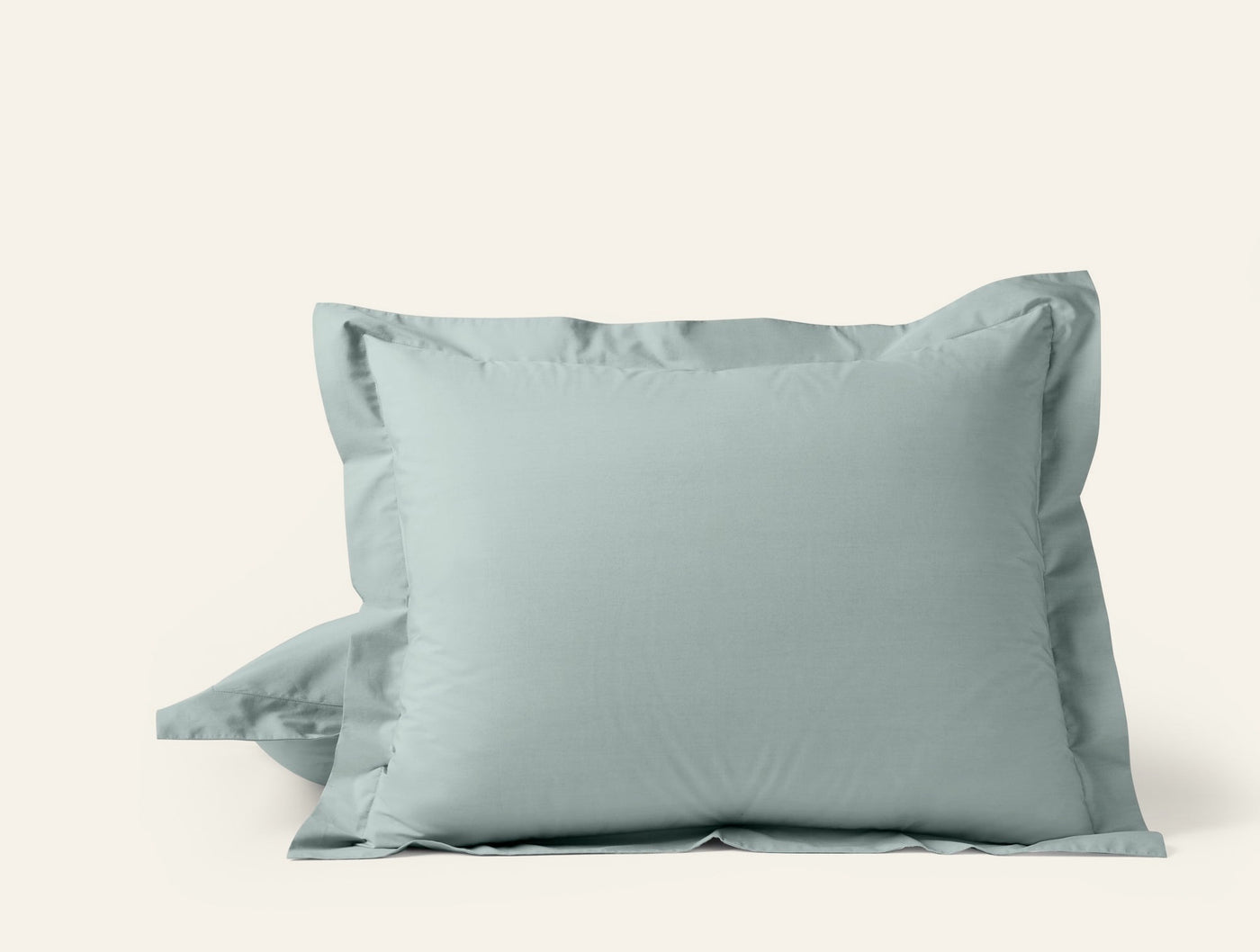Sage green percale pillow shams stacked, showing tailored flange edge detail.