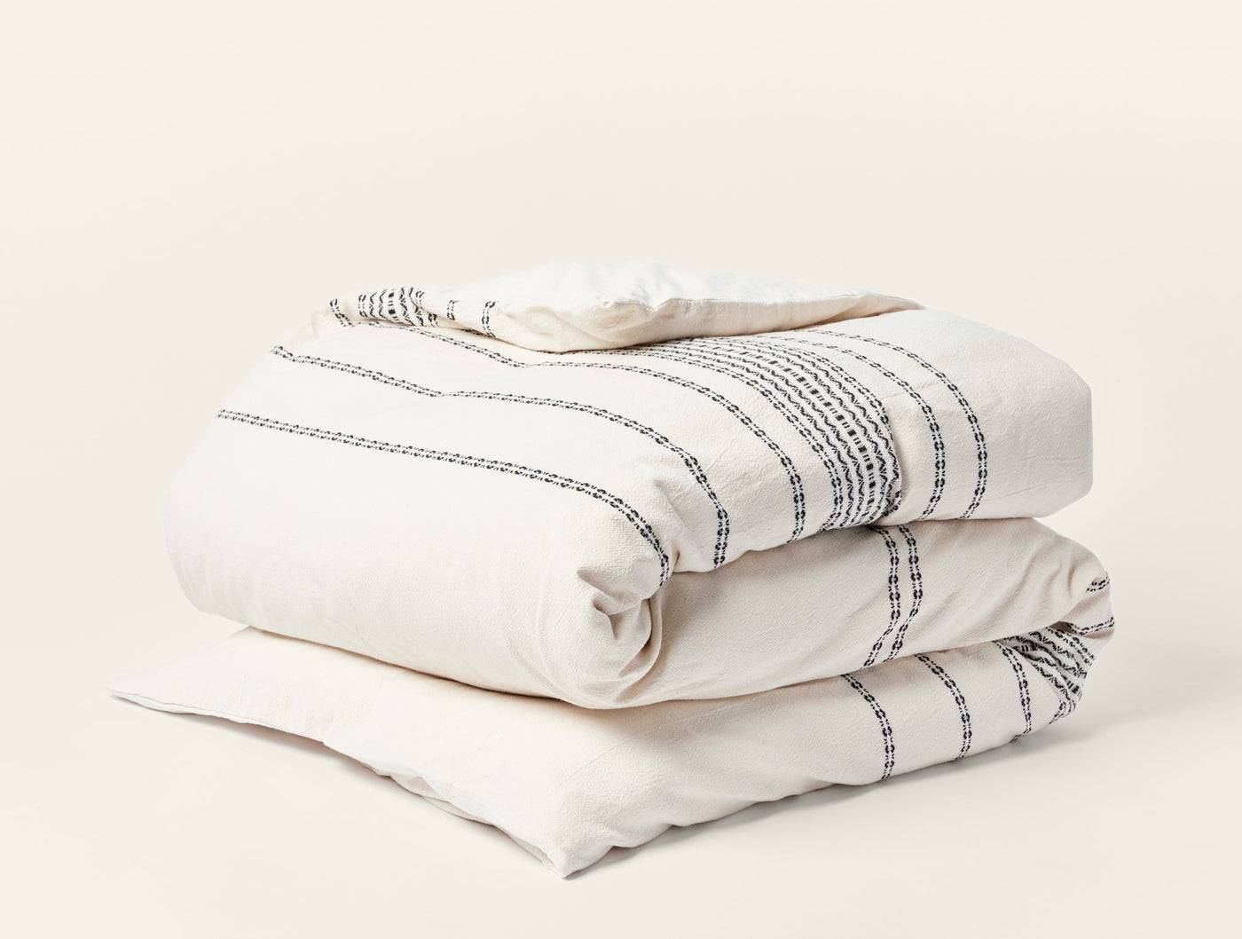 Coyuchi Rippled Stripe duvet cover in ivory with charcoal stripe detail, neatly folded.