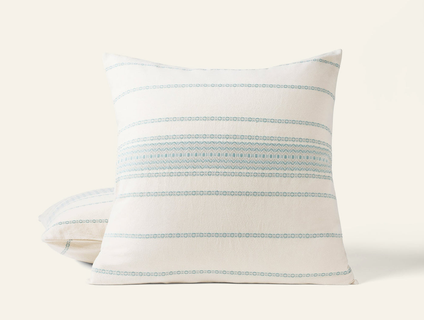 Coyuchi Rippled Stripe sham in ivory with aqua embroidered horizontal stripes, angled view.