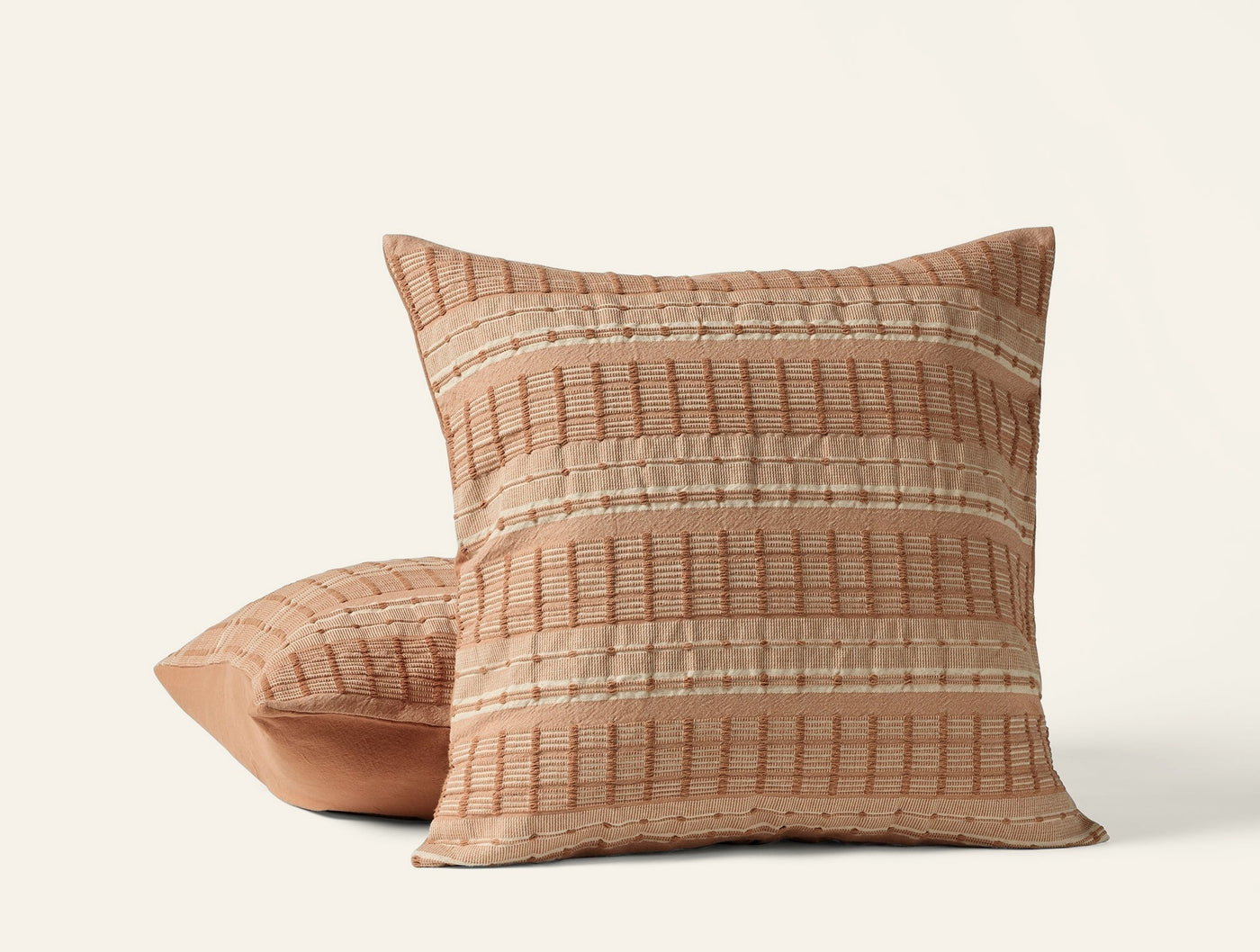 Coyuchi Sea Ridge pillows stacked, terracotta with woven stripe texture detail.