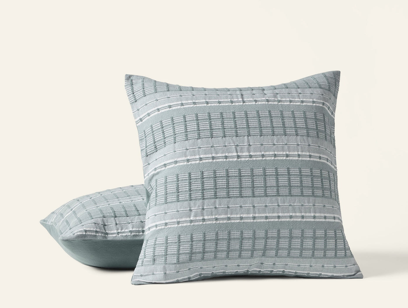 Coyuchi Sea Ridge pillow covers in sage, showing woven grid stripe pattern on stacked pair.