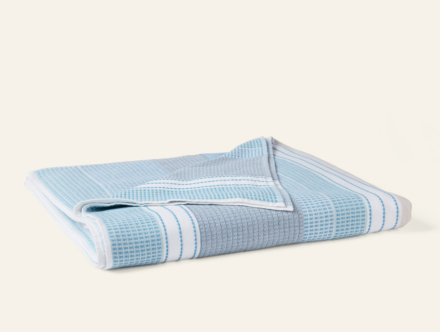 Folded sky blue waffle-weave beach towel with white stripe border detail.