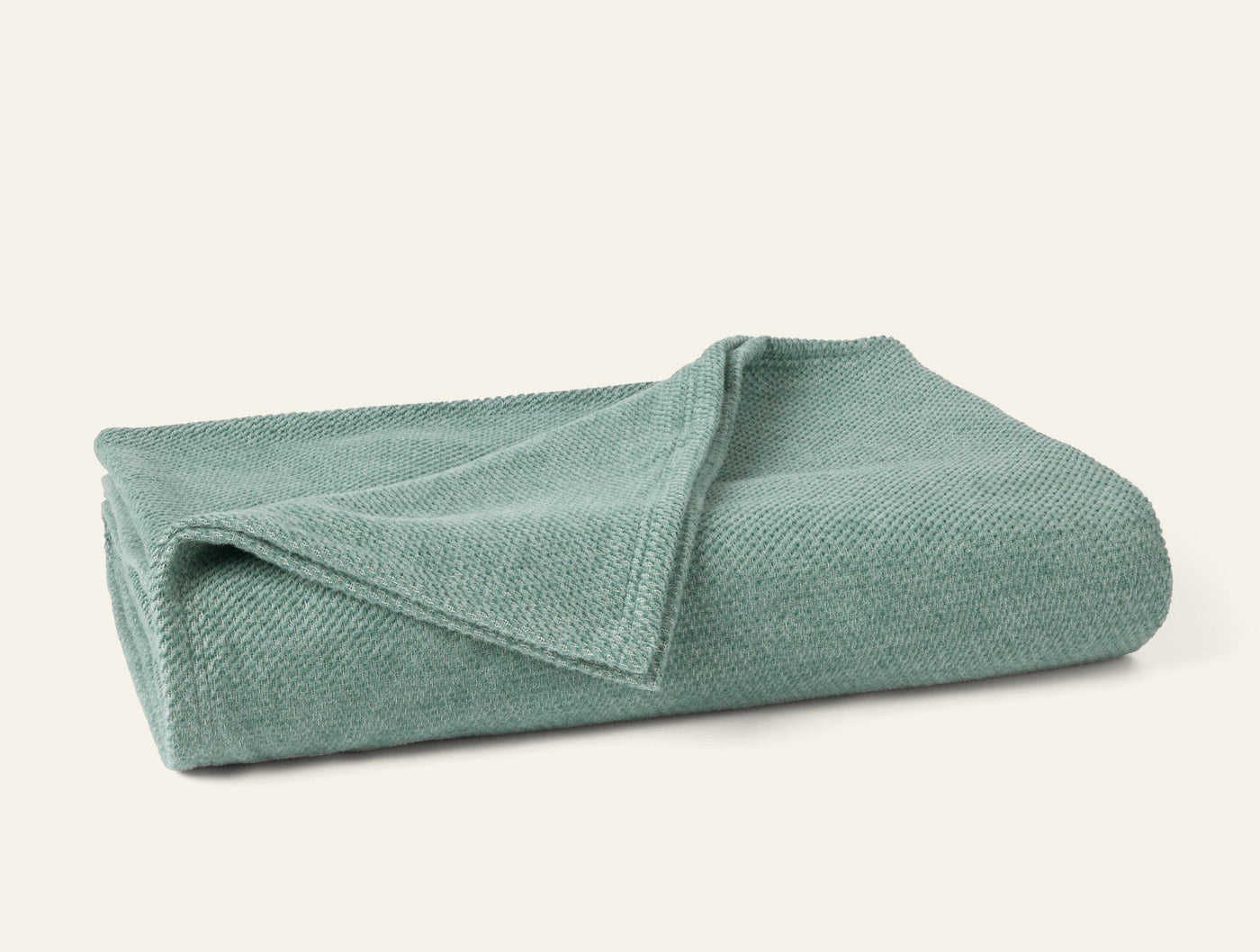 Folded sage green Coyuchi Sequoia blanket showing textured knit weave detail.