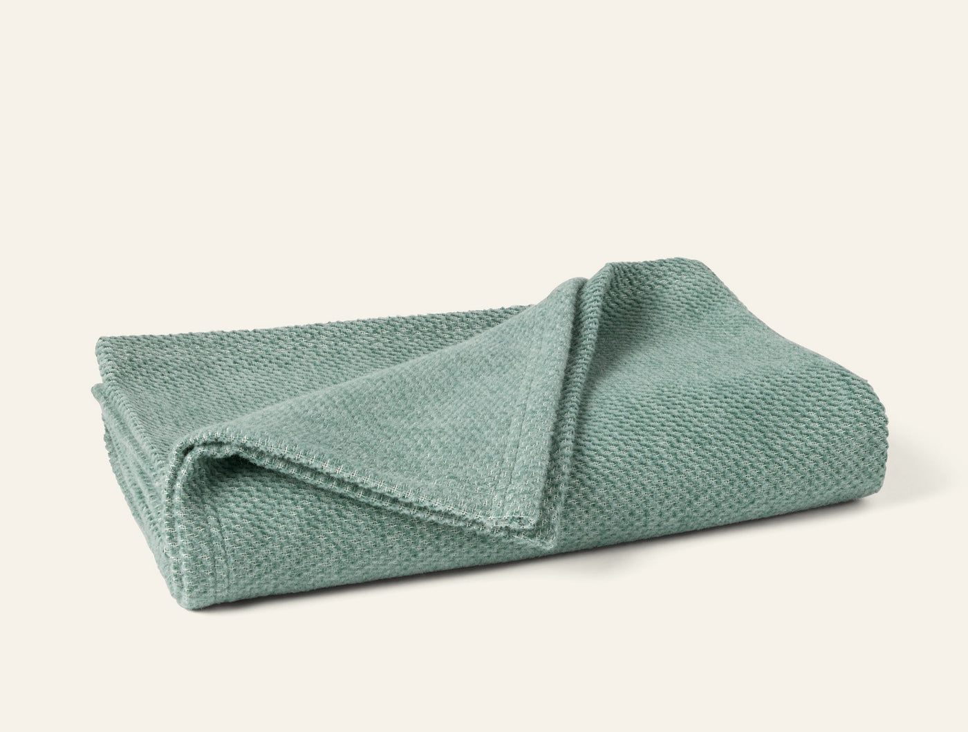 Coyuchi Sequoia throw folded, showing sage green textured weave detail.