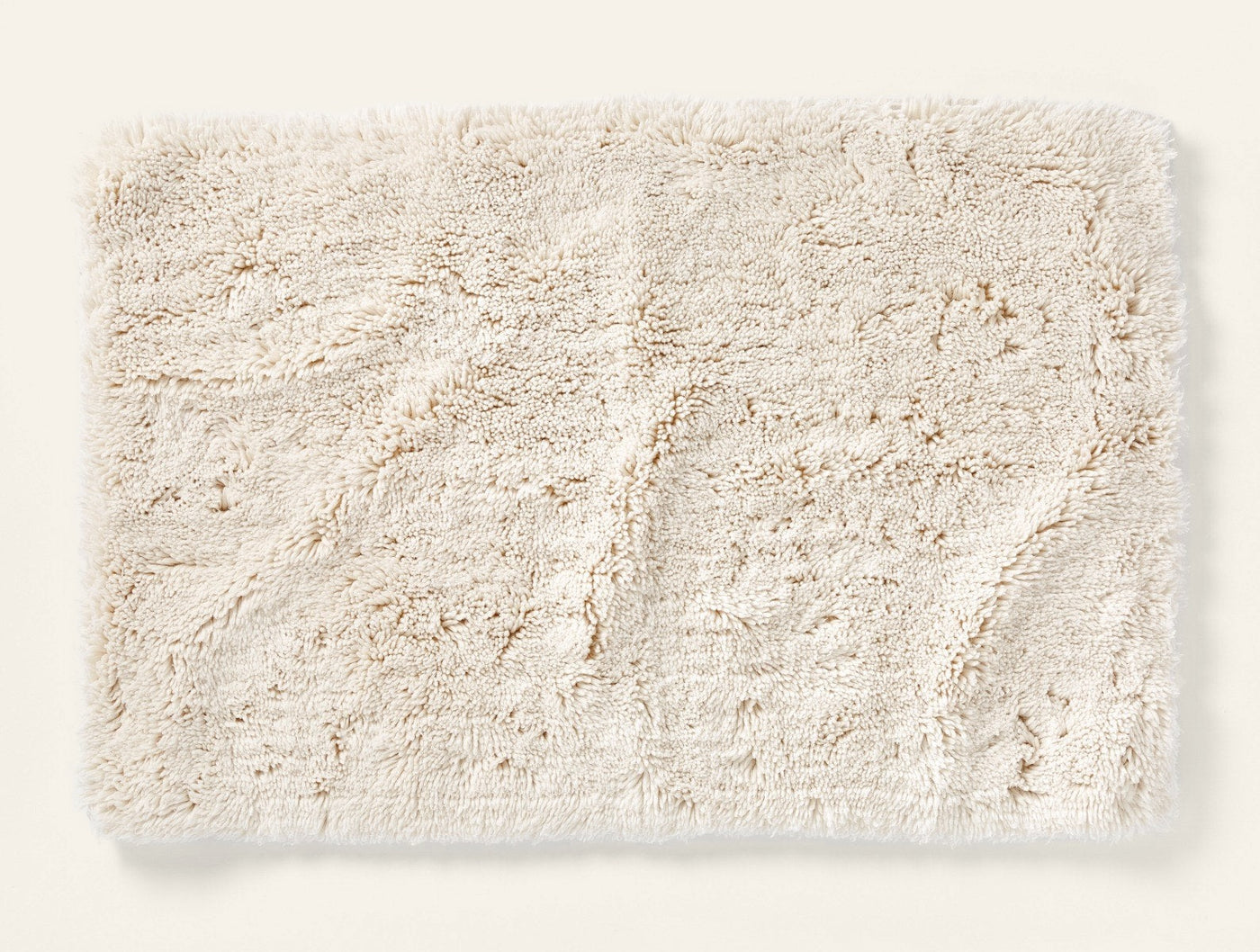 Overhead view of ivory Coyuchi shag bath rug showing plush texture and tonal pattern.