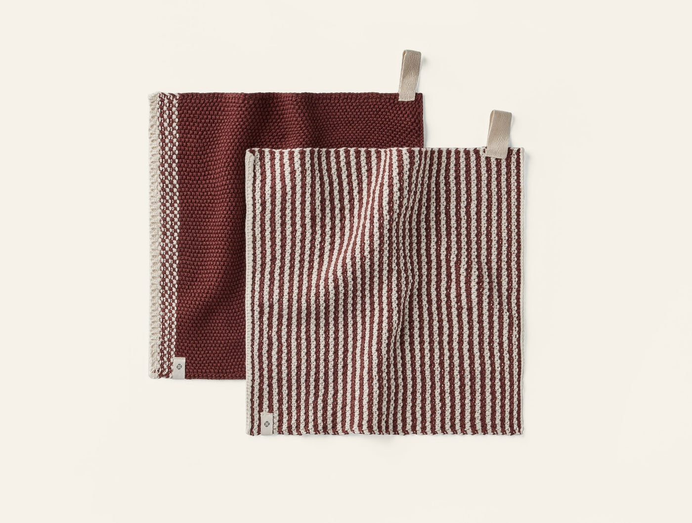 Coyuchi Shasta dish cloths in burgundy stripe and solid, showing both cloth loop tabs.