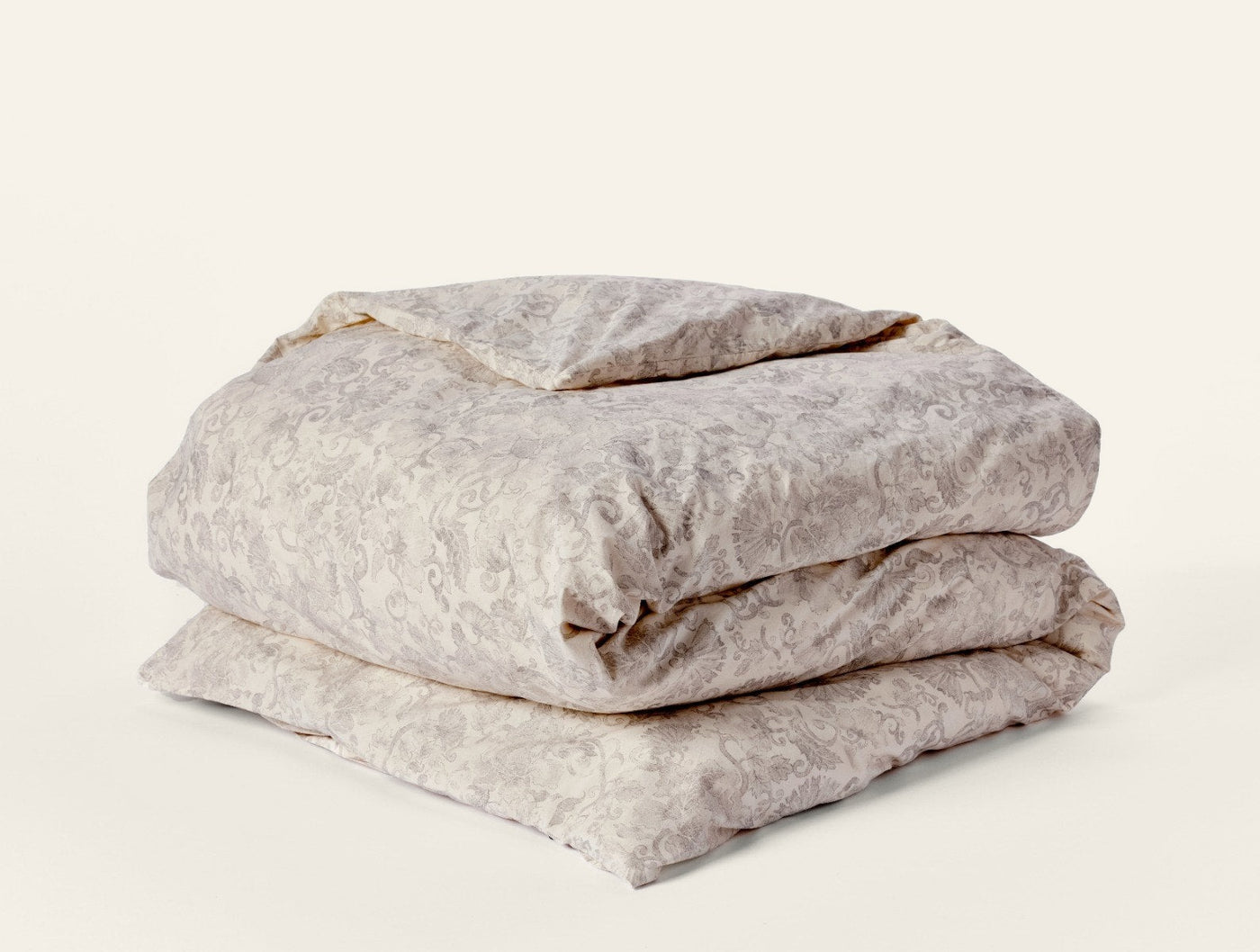 Folded ivory duvet cover with subtle tone-on-tone floral damask print, stacked view.