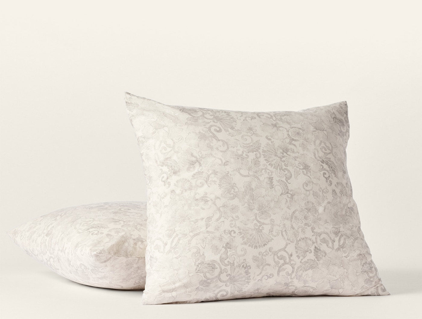 Close-up of two stacked ivory Coyuchi Solana Print shams with tone-on-tone floral damask.