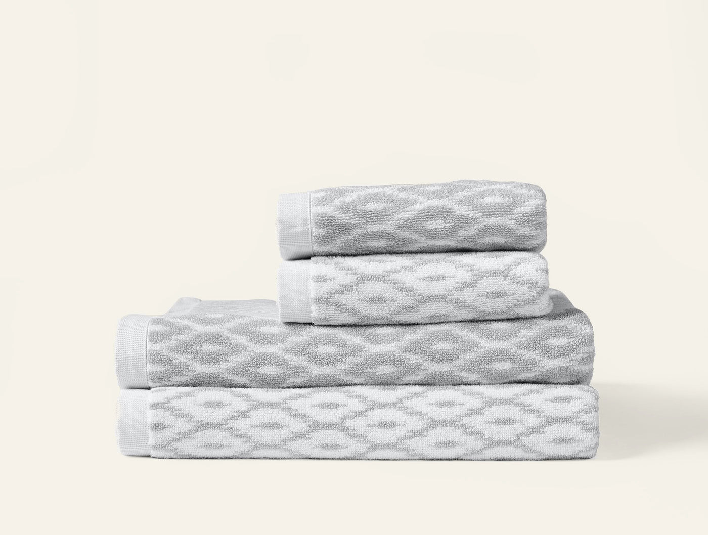 Close-up of stacked Coyuchi Stinson towels in grey diamond jacquard pattern with white trim.