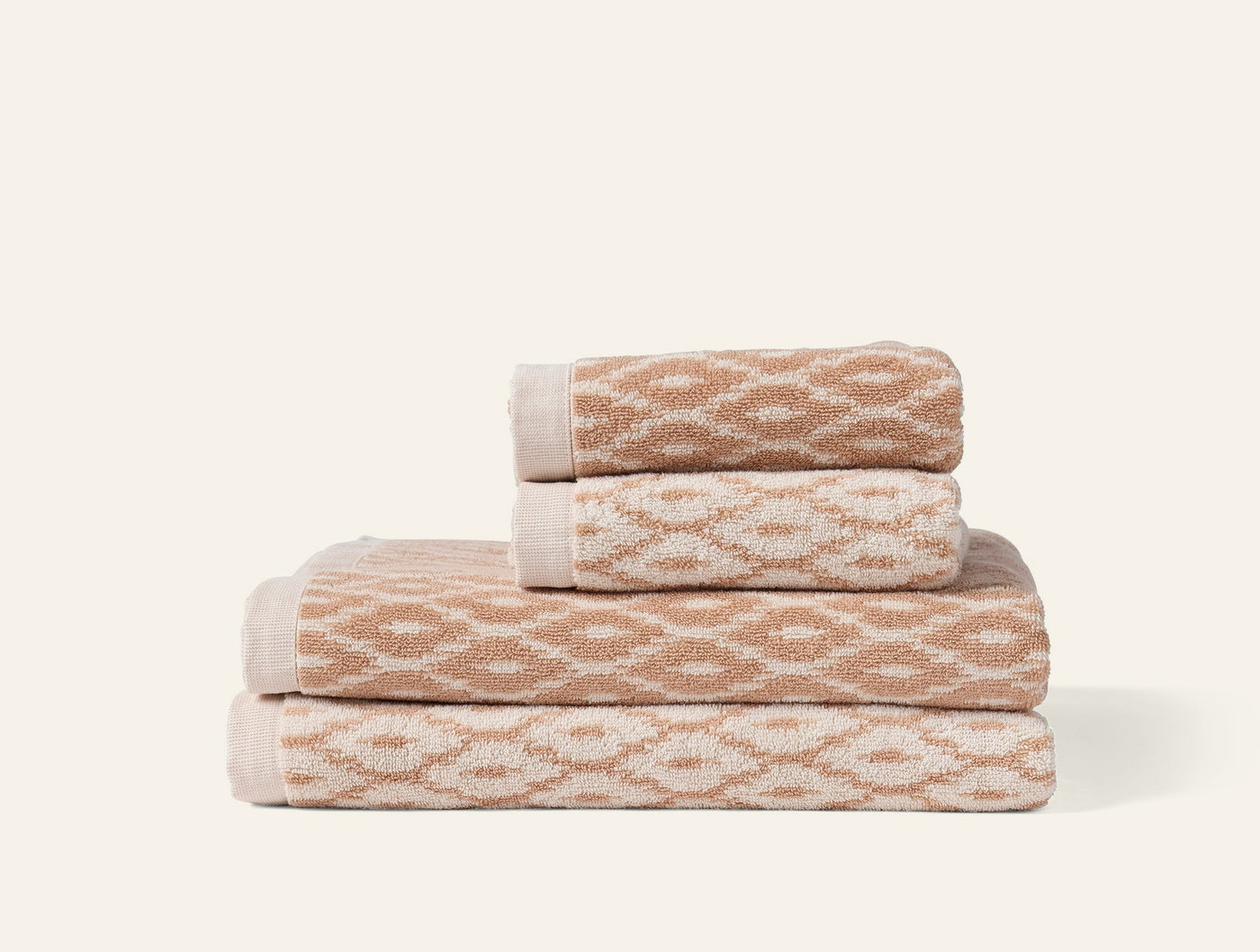 Close-up of stacked Coyuchi Stinson towels in sand with geometric diamond jacquard weave.