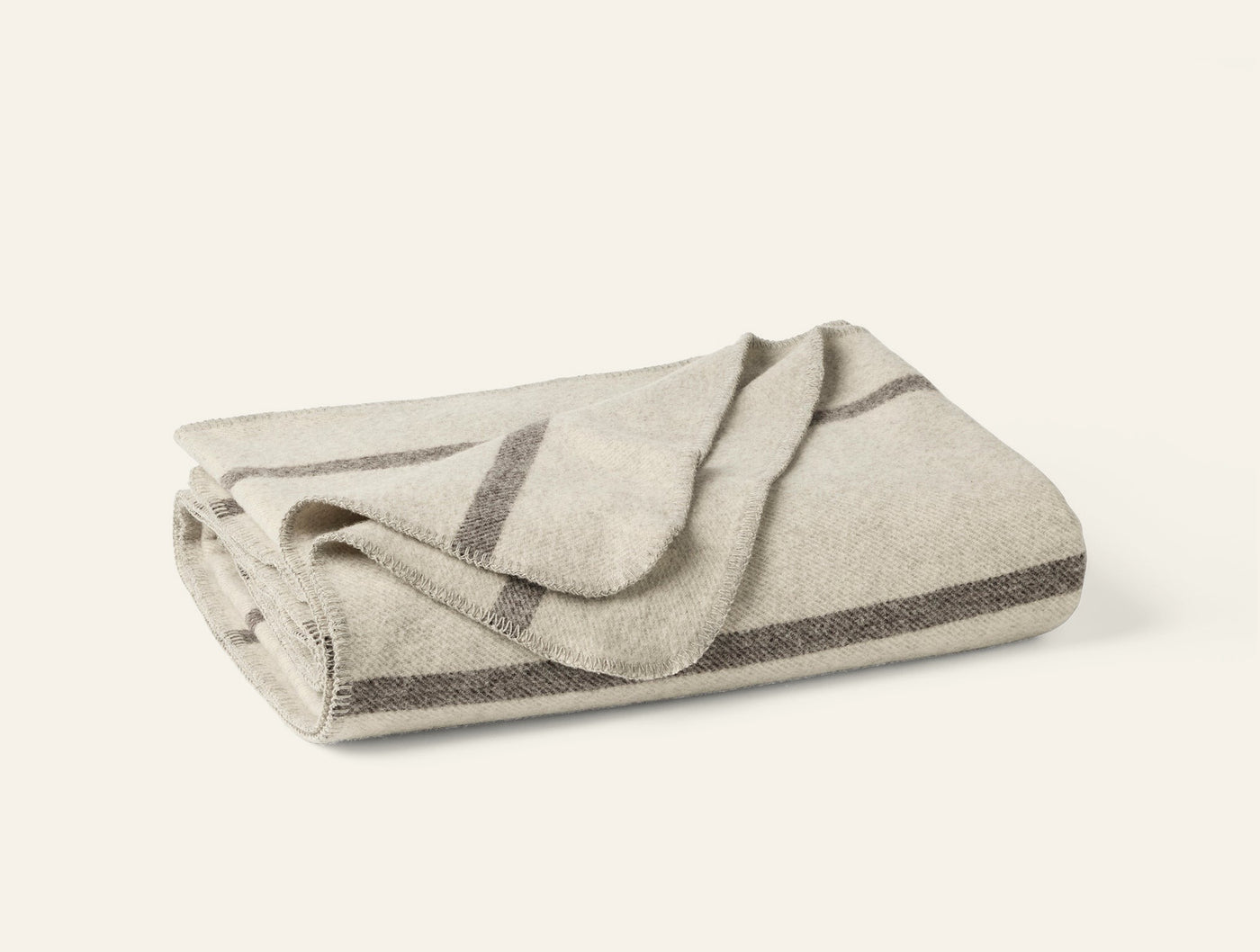 Close-up of folded ivory wool throw with charcoal stripe detailing along edges.