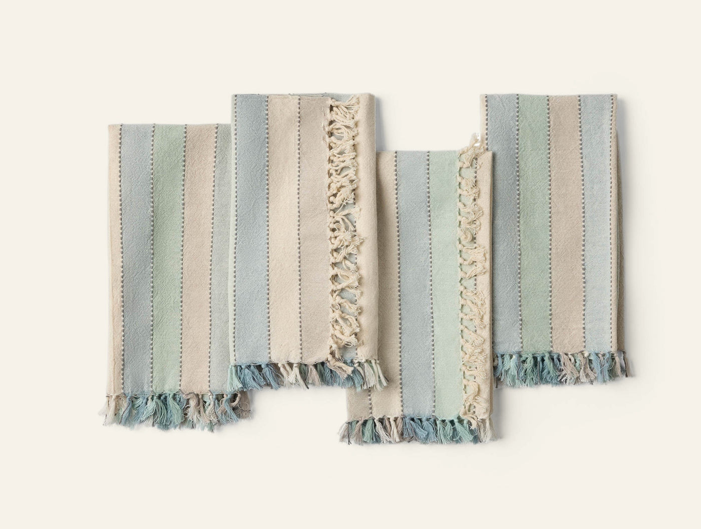 Four Coyuchi Tilden napkins flat-lay showing fringe edges and blue-green stripe weave detail.