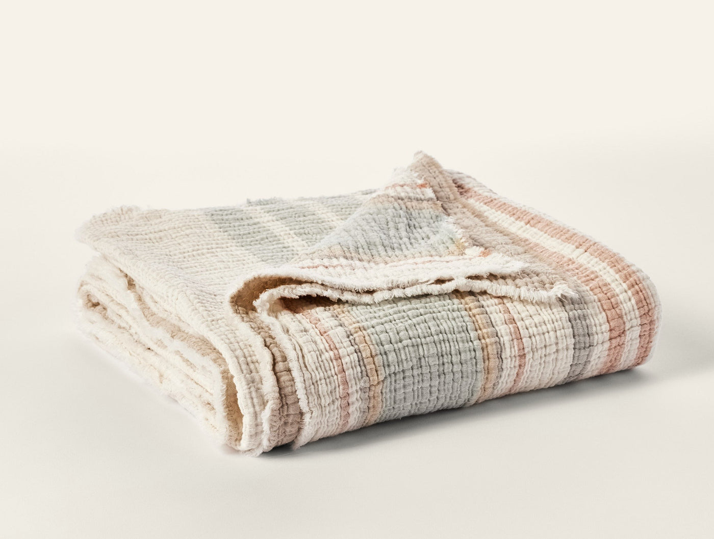 Coyuchi Topanga Matelassé throw folded, ivory with sage and terracotta plaid weave.