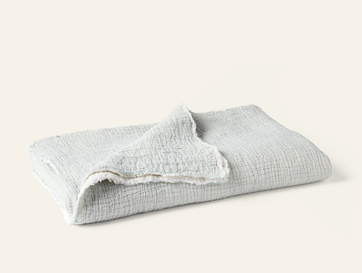 Folded Coyuchi Topanga Matelasse throw in mist, showing crinkled cotton texture.