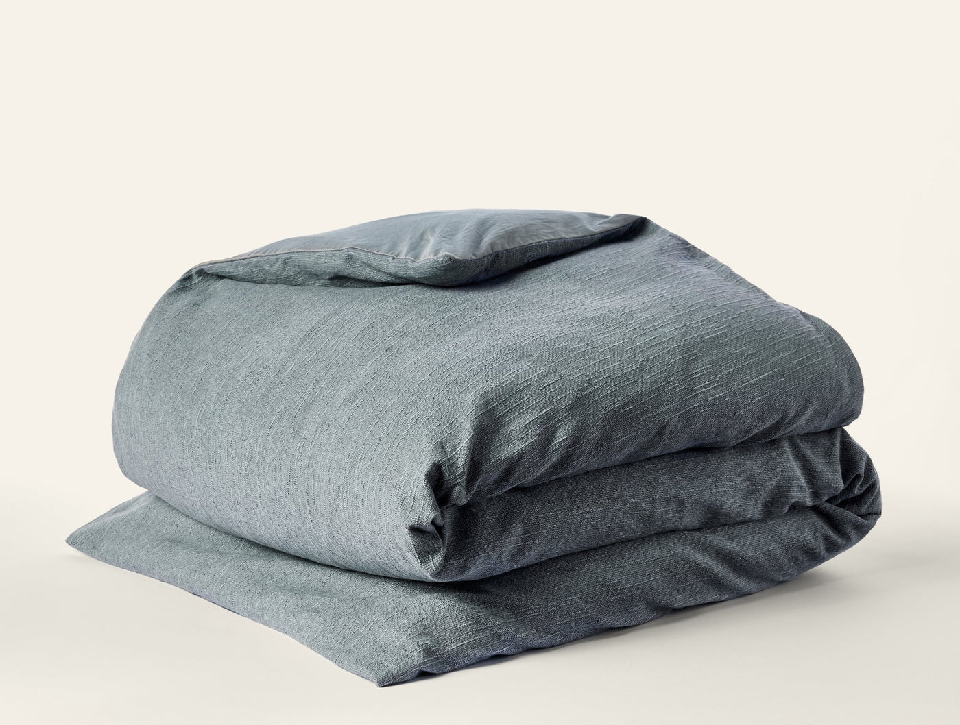 Slate blue-green linen duvet cover folded neatly, showing natural heathered texture.