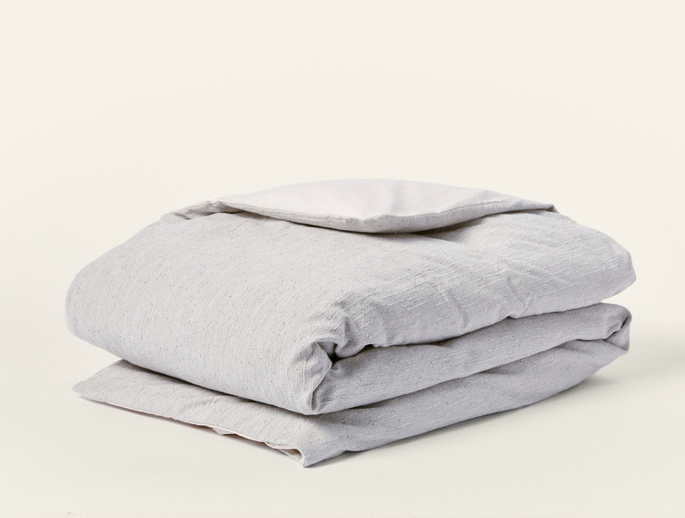 Folded dove grey linen duvet cover with natural reverse, showing textured weave.