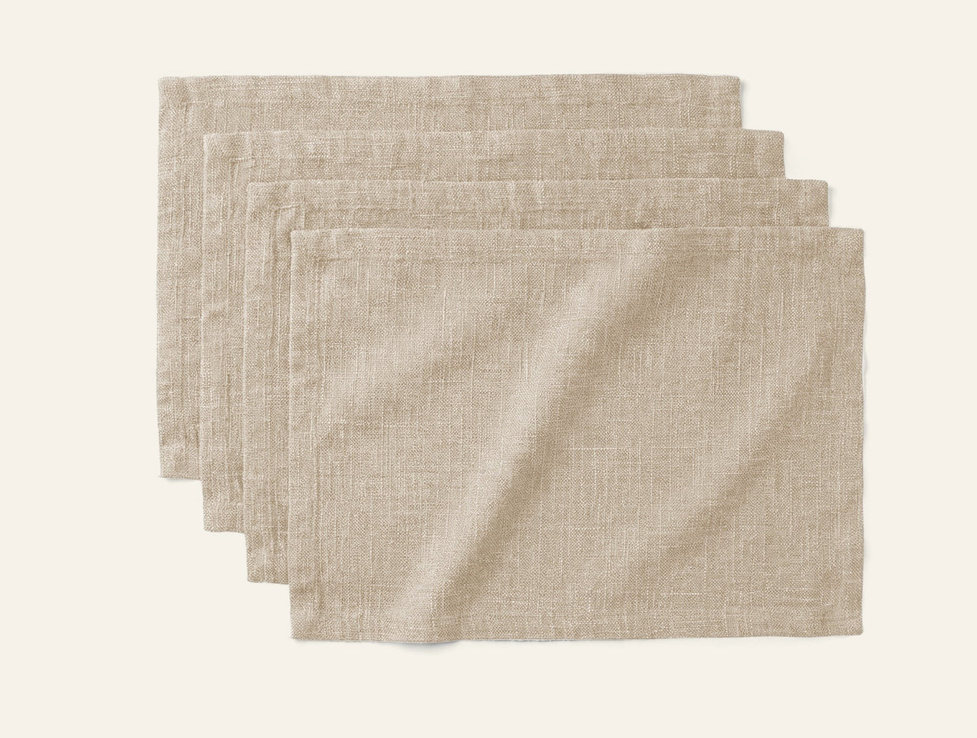 Four stacked Coyuchi Toro Canyon placemats in natural linen with visible woven texture.