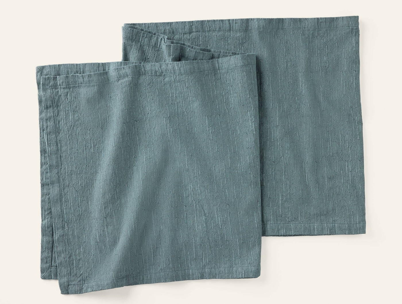 Pair of slate blue linen napkins folded flat, showing subtle woven texture.