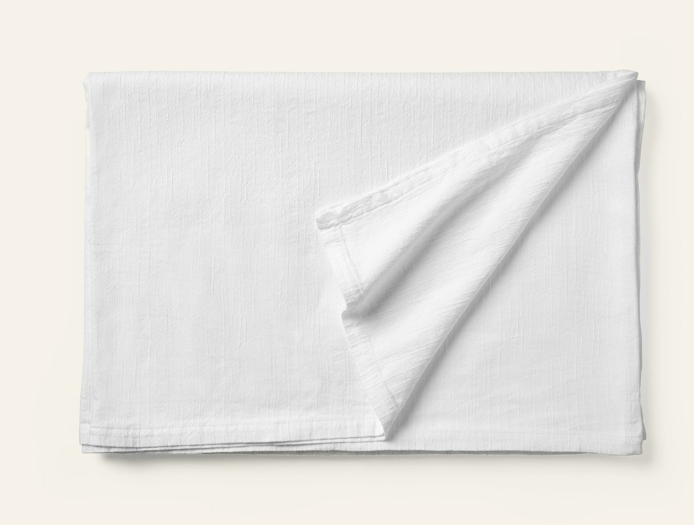 Coyuchi Toro Canyon tablecloth in white, folded to show subtle woven texture.