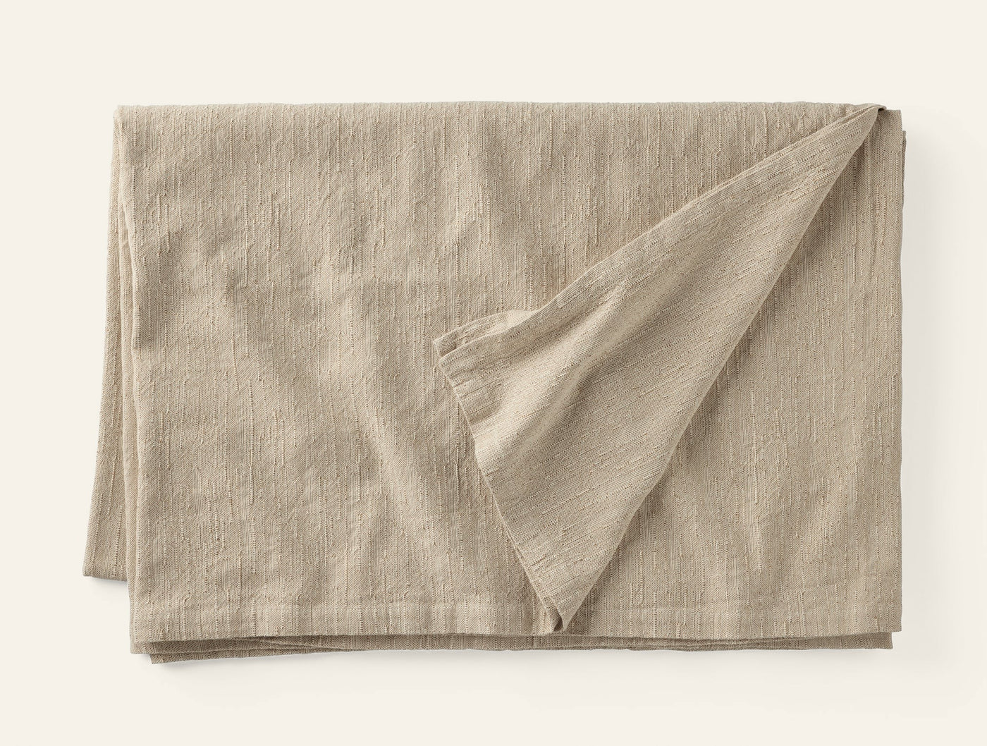 Corner fold detail revealing ivory underside of Coyuchi Toro Canyon linen tablecloth in oat.