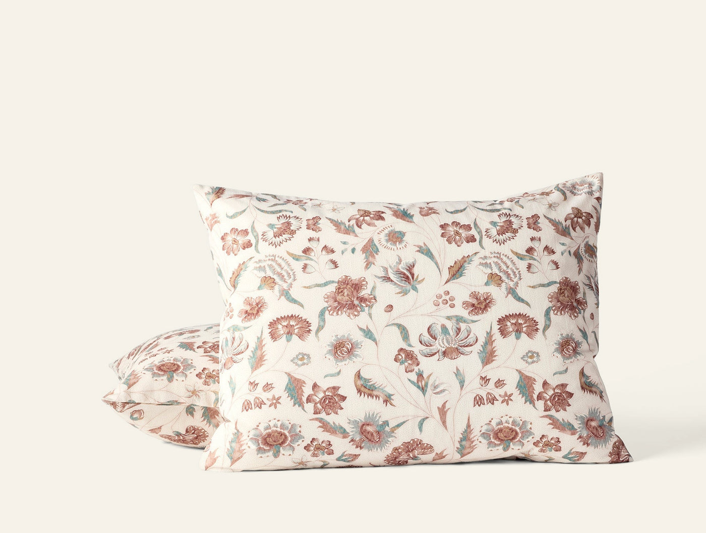 Terracotta and sage floral print on ivory cotton pillowcase, two shams stacked.