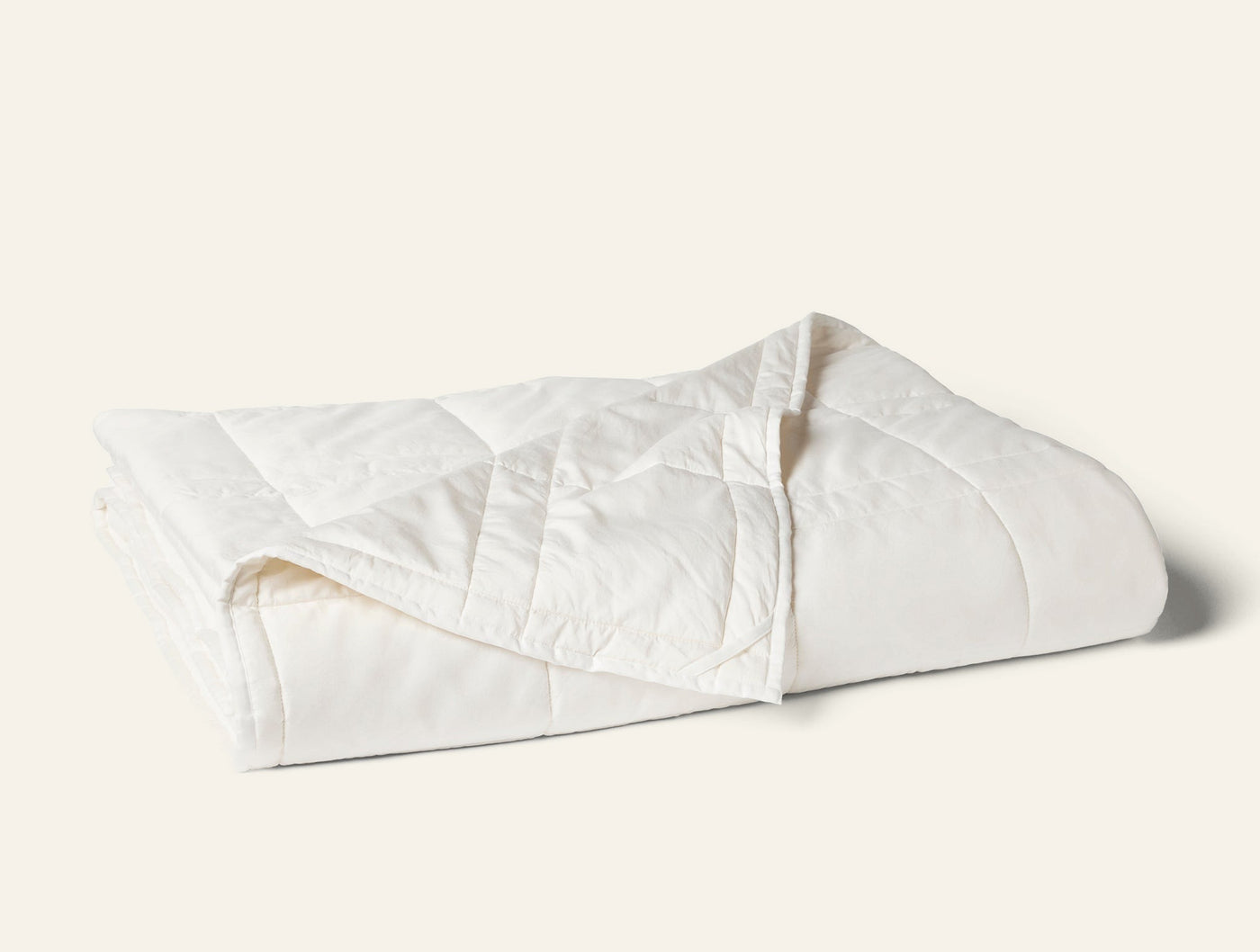 Coyuchi Washable Wool Filled Comforter in ivory, folded to show diamond quilt stitching.