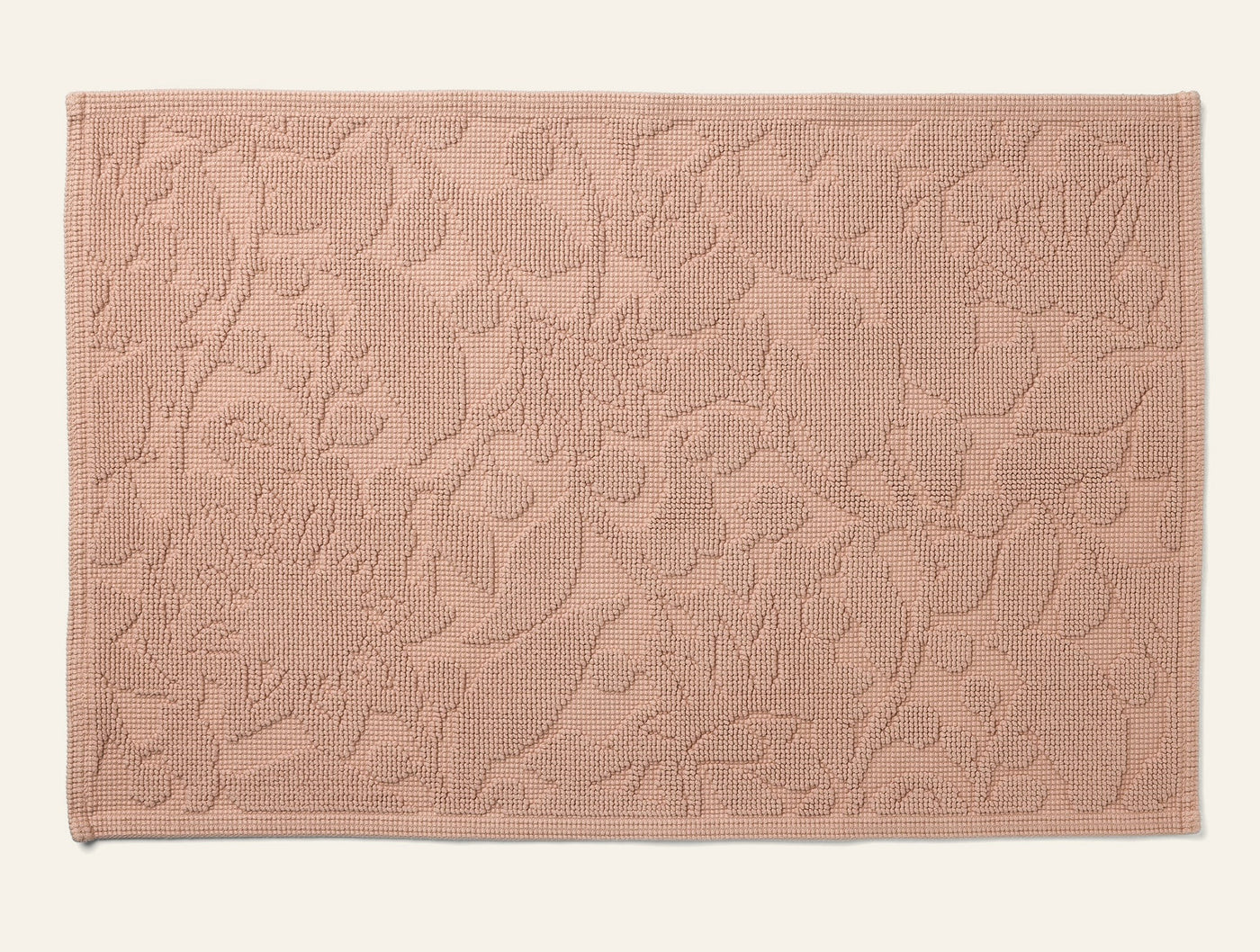 Coyuchi Wildflower bath rug in blush with tonal jacquard floral pattern, flat lay.