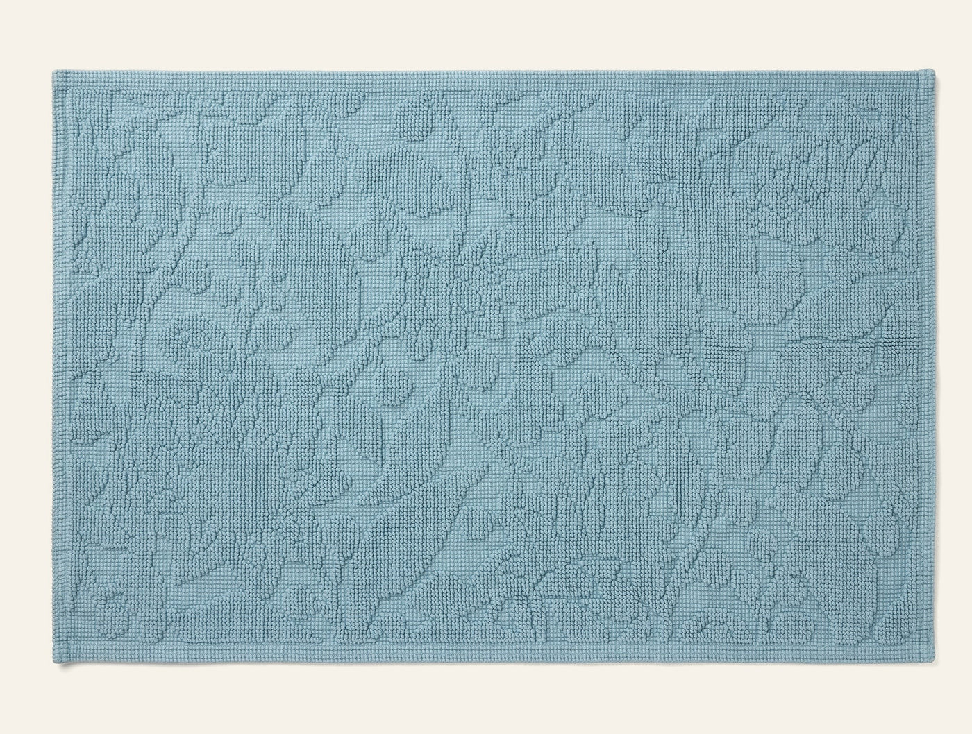 Coyuchi Wildflower bath rug in slate blue with tonal floral jacquard texture, flat lay view.