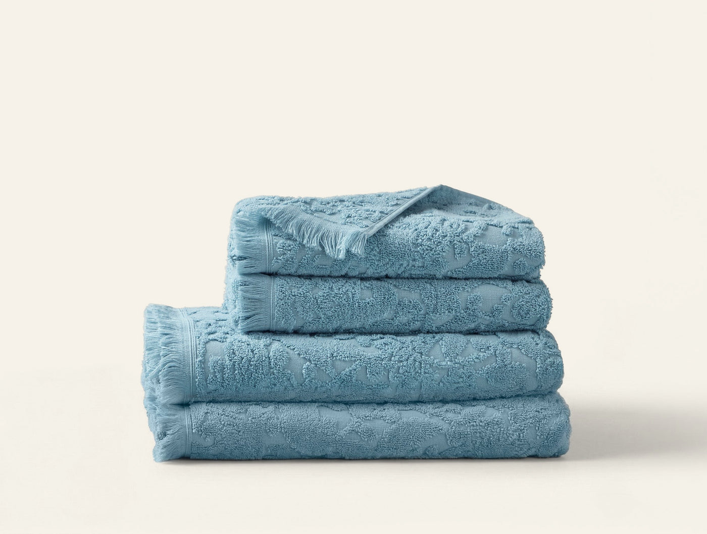 Close-up of stacked Coyuchi Wildflower towels in sky blue with floral jacquard texture.