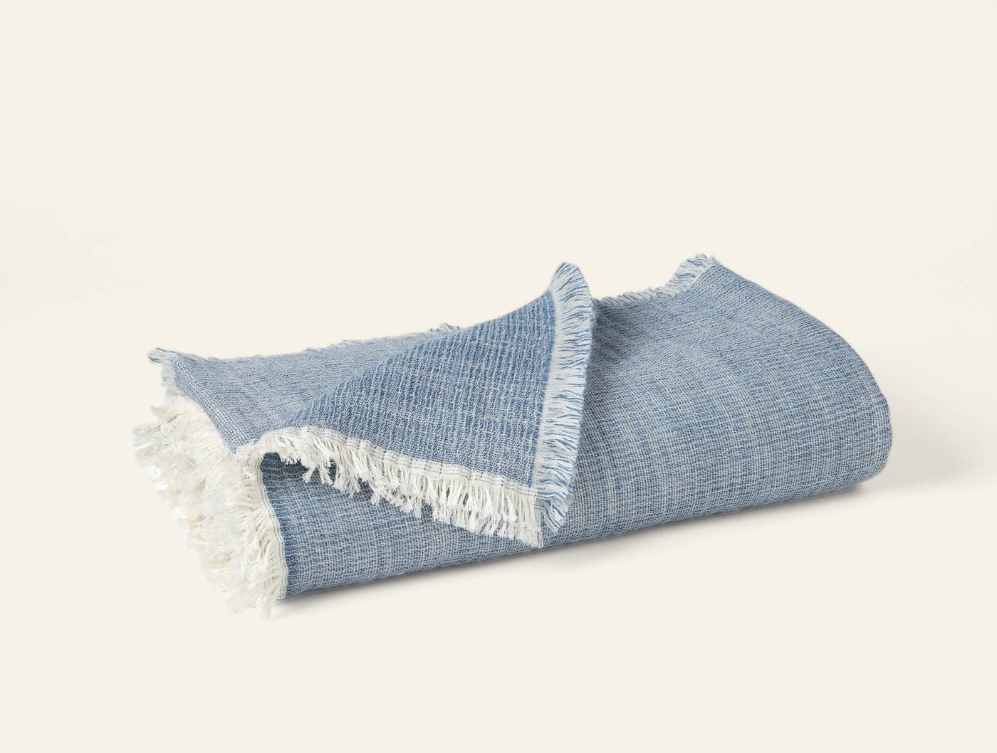 Coyuchi Willow throw in slate blue, folded, with cream fringe trim detail.