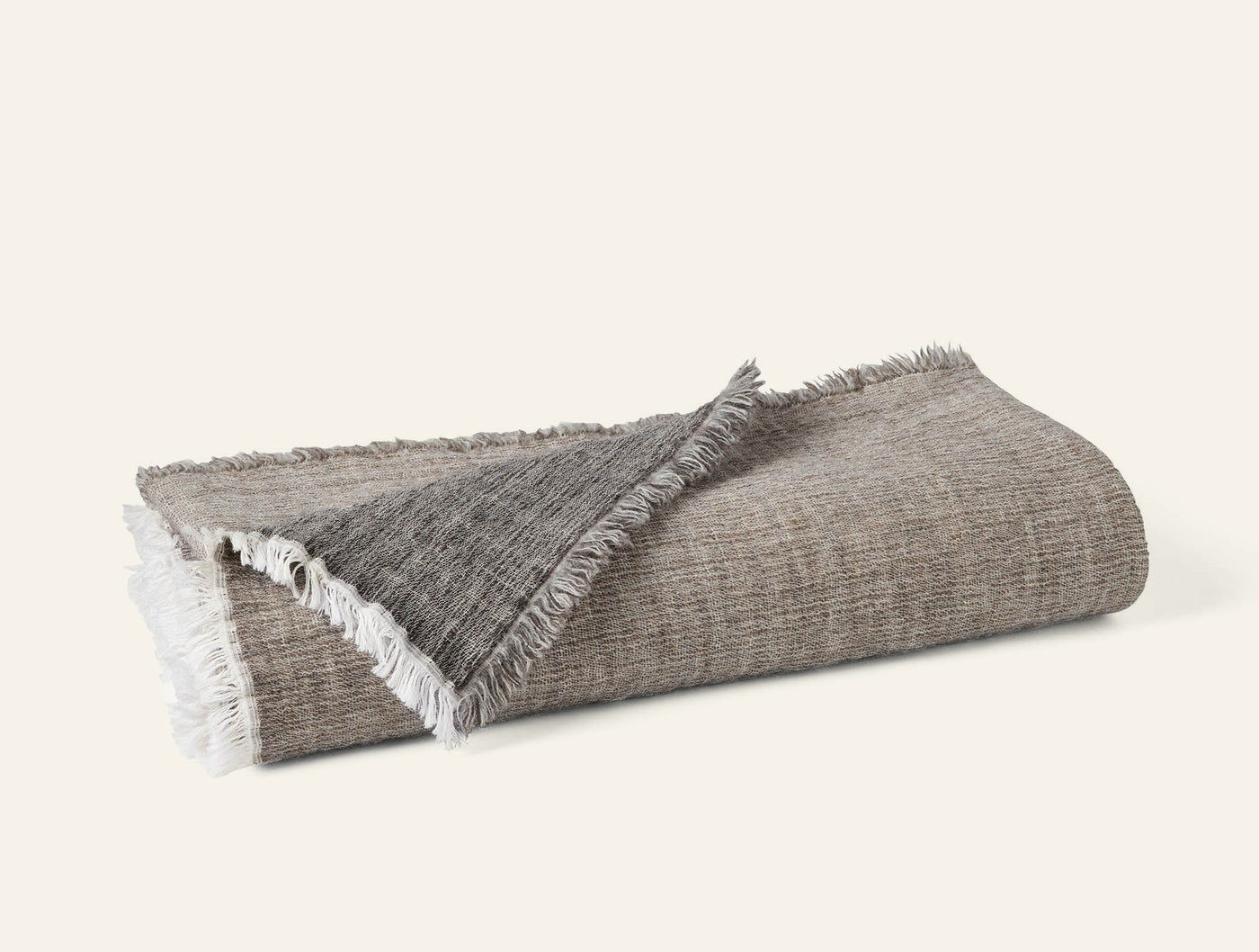 Folded throw showing contrast between taupe herringbone face and charcoal reverse, with fringe trim.