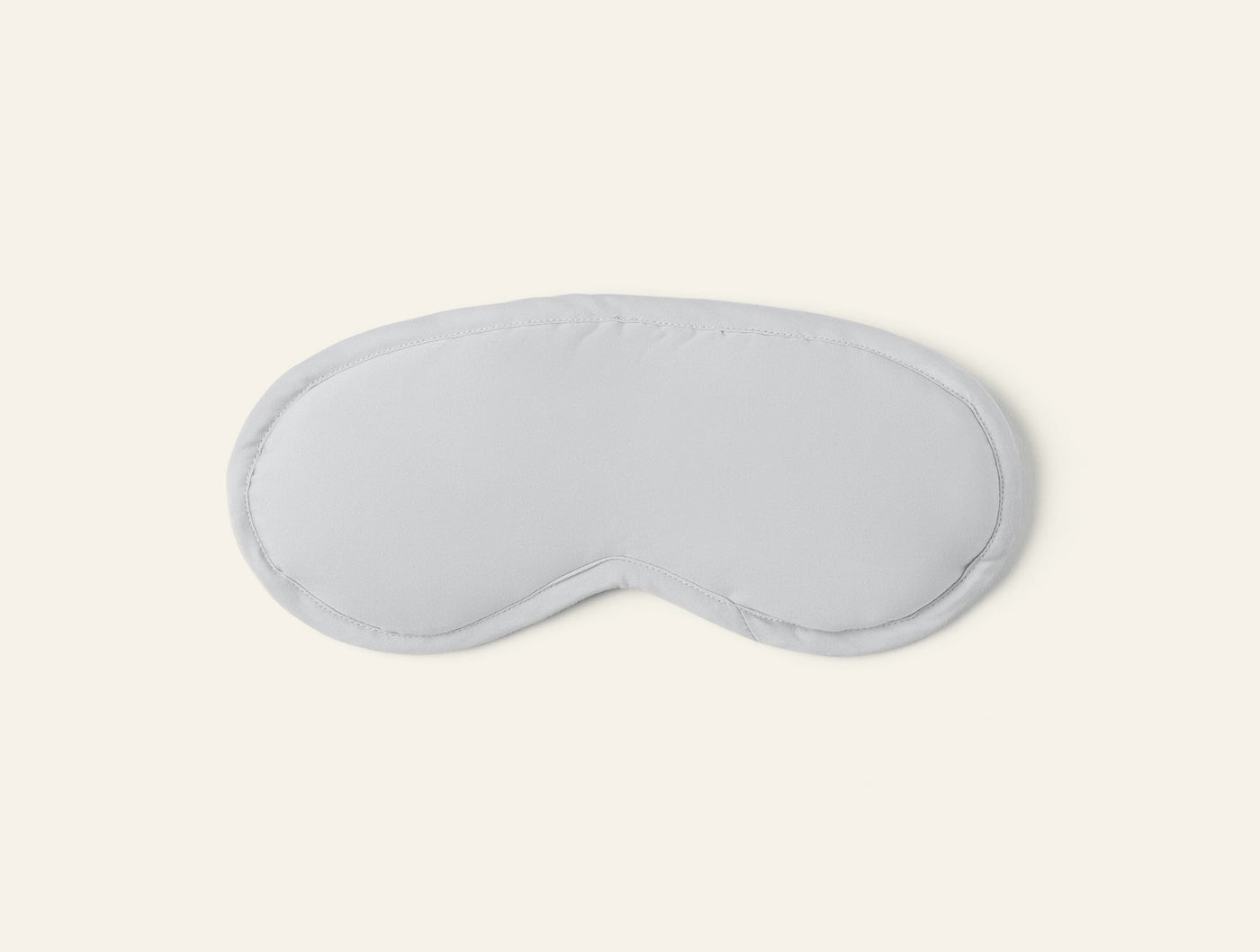 Flat lay of a white sateen eye mask with piped trim detail.