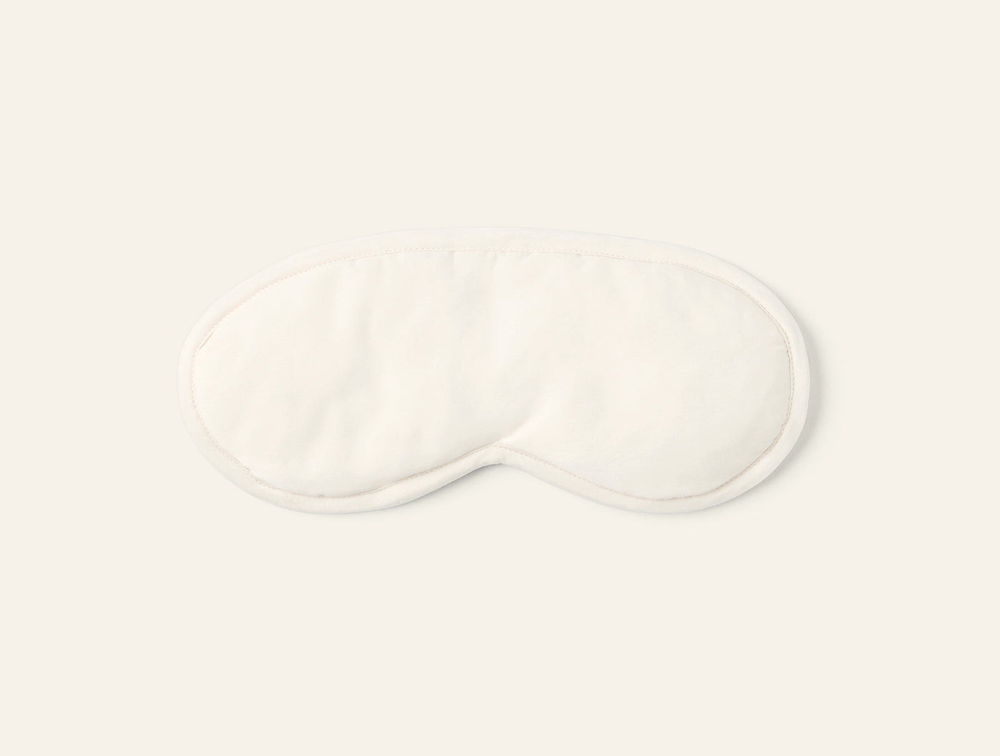 Ivory sateen eye mask shown from above on a light grey background.