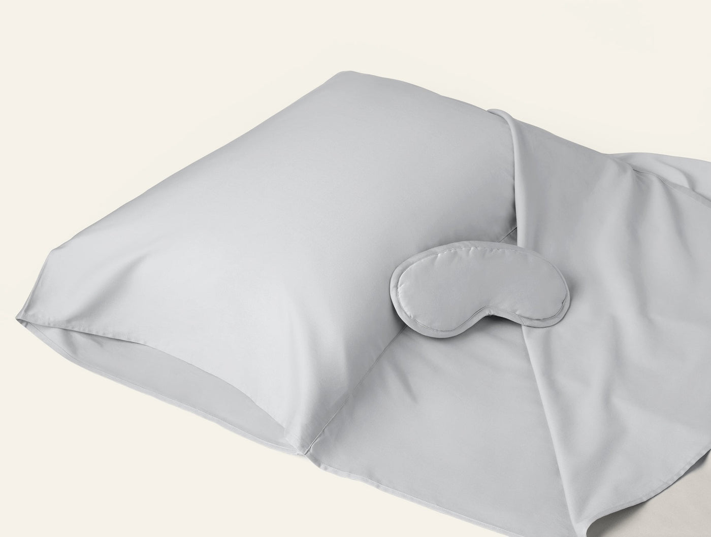 Coyuchi Cloud Soft Sateen travel sack in silver with matching sleep mask, angled view.