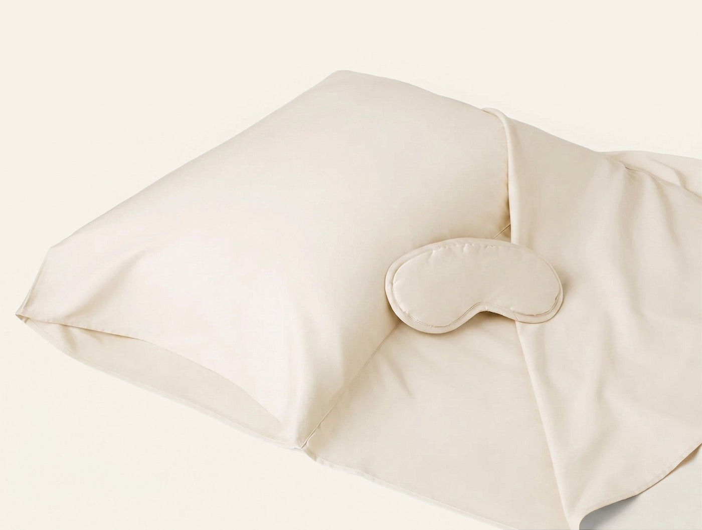 Coyuchi Cloud Soft Sateen travel sack in ivory with matching sleep mask, angled view.