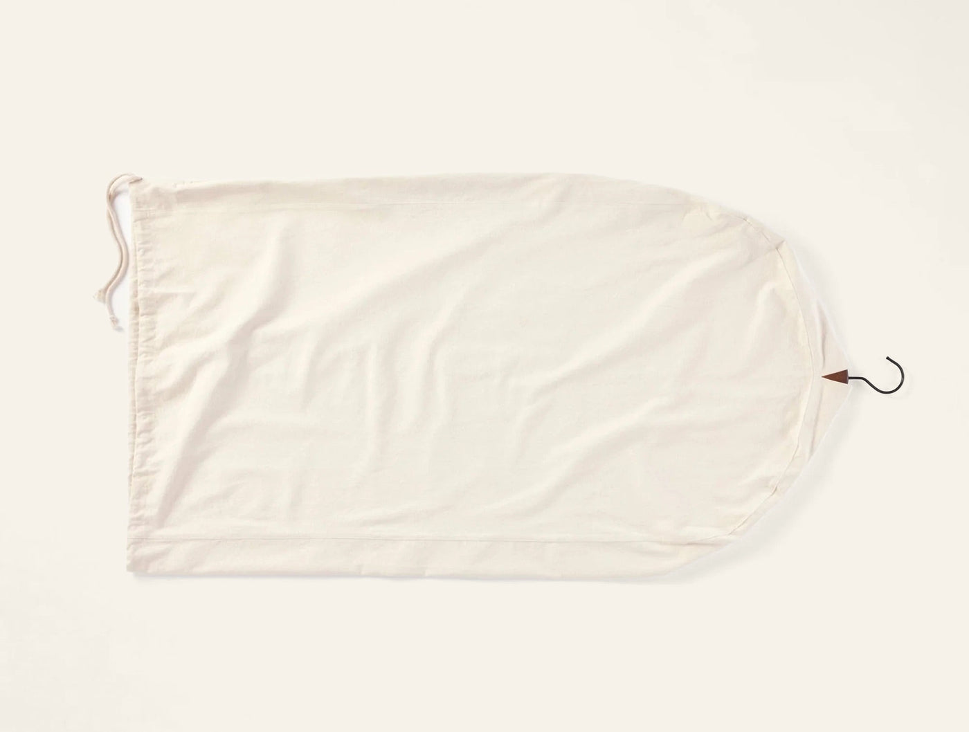 Coyuchi Conserve ivory cotton garment bag with drawstring closure and metal hook.