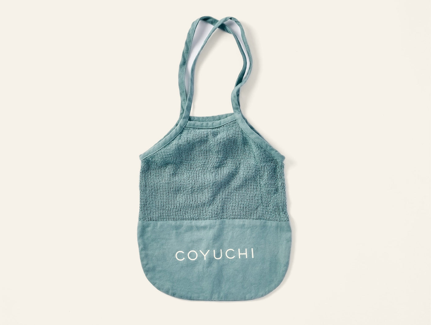 Coyuchi tote bag in sage green with white logo and textured upper panel.