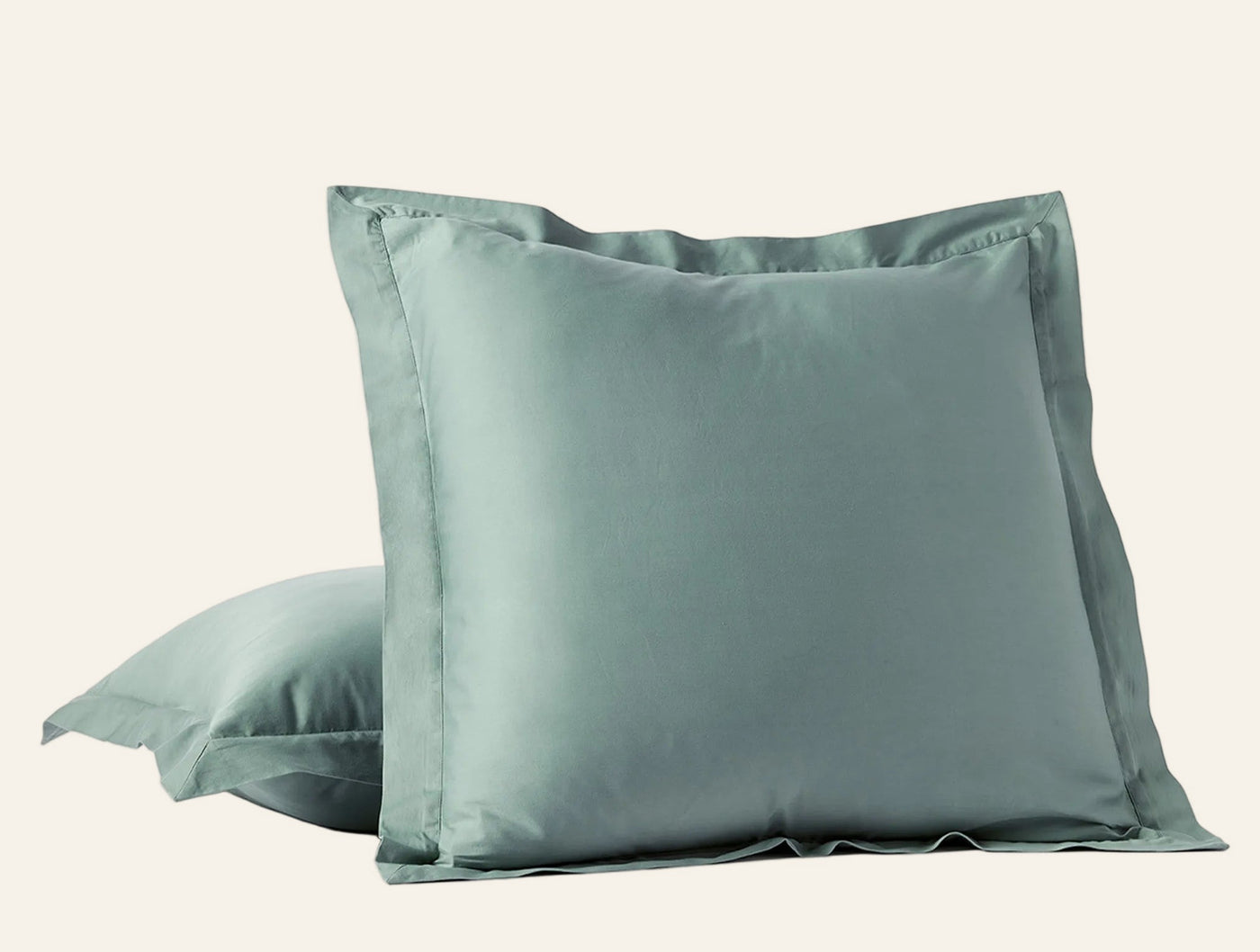 Two sage green sateen pillow shams stacked, showing tailored flange edge detail.