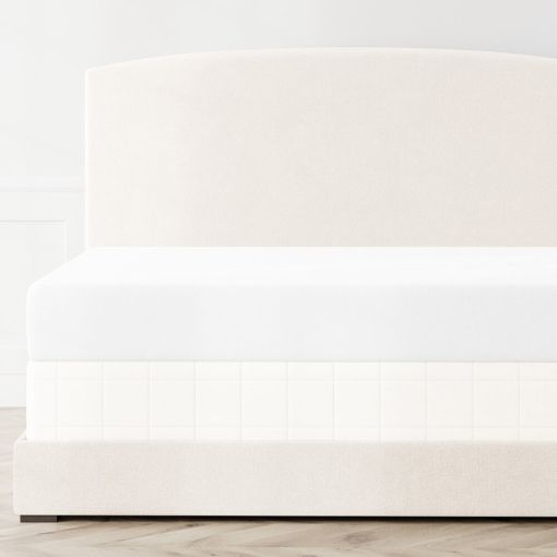 Ann Gish Macau box spring cover in ivory, styled on a cream upholstered bed frame.