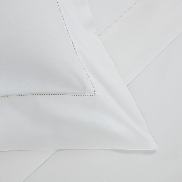 Frette’s Single Ajour | Sheet Set, crafted in Italy from luxurious cotton sateen, features subtle stitched detailing and an elegant open hemstitch, displayed neatly on the bed.