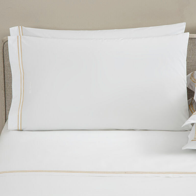 Made from cotton percale, the Frette Classic | Pillowcase Set by Frette features white pillowcases accented with a simple gold stripe, bringing a touch of luxury to any bedroom.