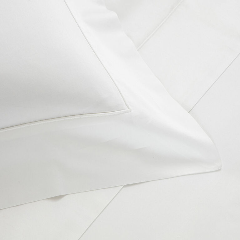Close-up of the Grace | Duvet Cover by Frette, featuring a neatly arranged white pillow and bedsheet set in luxurious cotton sateen for an elegant bedding accent.