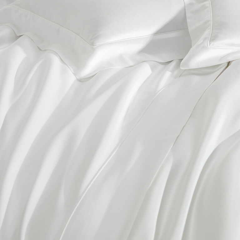 The Grace | Duvet Cover by Frette features white cotton sateen bedding with two neatly arranged pillows, offering a smooth texture, subtle folds, and an elegant, refined finish.